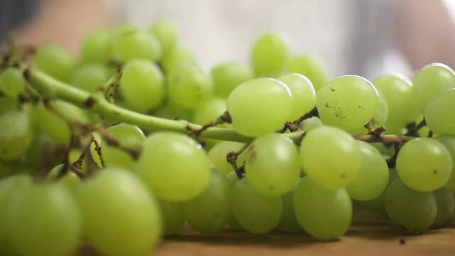 Close-up to green ripe grape on a wooden board in kitchen