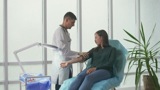 Planned Preventive Medical Examination of a Young Woman in the Clinic. The Doctor Measures the Blood Pressure of the Patient in the Office of the Clinic. Health Insurance Medical Service Concept.