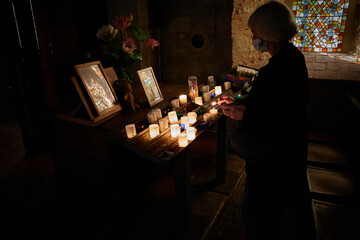 Woman with facemask burning a candle in a church hoping here family wil be saved from Covid. 
