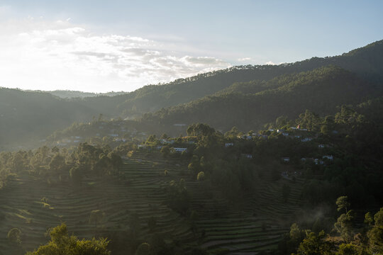 Beautiful landscape of a village based in mountains captured during sunset. View of terrace farms with the crops.
