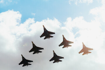 A squadron of jet soldiers, fighters, and airplanes perform a maneuver against the background of a...