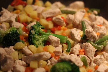 Prepare pilaf in a large frying pan. A dish of rice and pieces of vegetables. Steam comes from a hot lunch. Home kitchen. Pilaf is stirred with a wooden spatula.