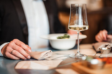 Obraz na płótnie Canvas glass of white wine on the table and hand