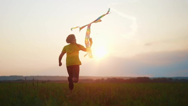 girl run with a kite in the park at sunset. fantasy happy family dream kid concept. child run park play with toy kite. girl kid wants to astronaut pilot. childhood fun free girl concept