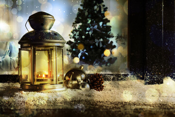 Lantern with candle, baubles and pine cone near window outdoors. Christmas eve