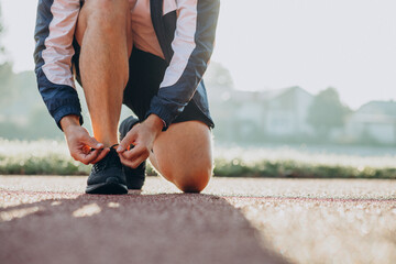 Man jogger tying shoelaces at stadim