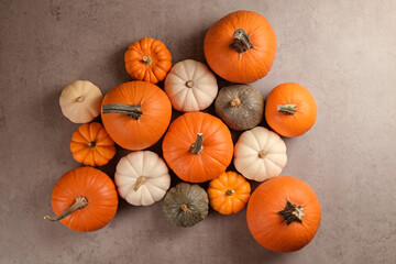 Bunch of pumpkins of different kinds, shapes and colors on grey stone background as a symbol of autumnal holidays with a lot of copy space for text.