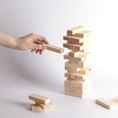Close-up of fingers prevents the jenga wood block from falling