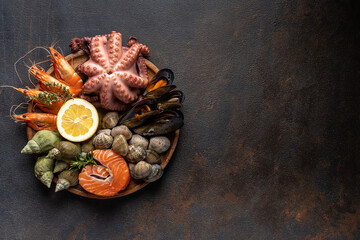 Raw fish, octopus, shrimp, snails on a stone plate. Seafood. Top view. Free space for copying.