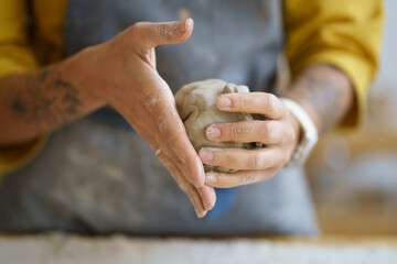 Female potter artist molding raw clay. Closeup of woman ceramist in dirty apron prepare for shaping pottery. Craftswoman hands work with earthenware. Art studio production and craftsmanship therapy