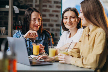 Three girls students preparing for exam with laptop in a cafe