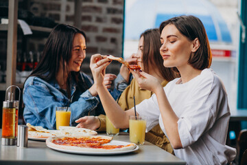 Three girls friends having pizza at a bar