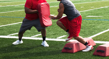 Football player running over red barriers into their coachs pad