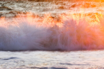 Colored splashes of the sea wave. Large ocean waves at sunset. Long exposure of the sea wave.