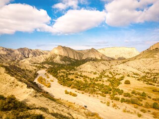 Aerial scenic view of Vashlovani national park protected area landscape with jeep on the road passing in the foreground