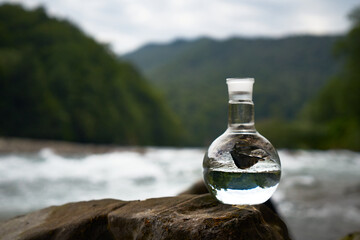 Bottle of drinking water on the shore of a mountain river.
