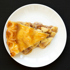 Fresh Homemade Salted Caramel Apple Pie on a white plate on a black surface, top view. Flat lay, overhead, from above.