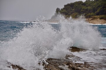 Obraz premium Big wave splash into croatian rocky beach during strong wind on Adriatic Sea. Horizon line.