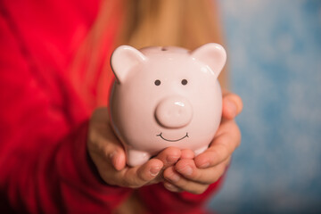 Small girl hands with piggy bank on blue backgound
