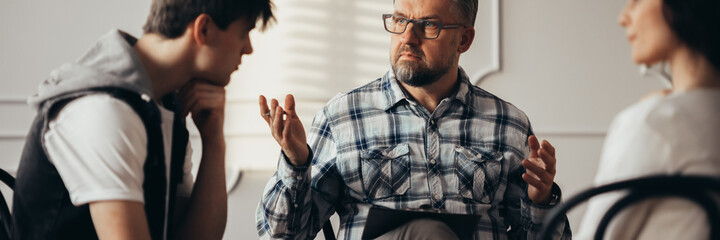 Psychologist talking to depressed teenager and his mum during th