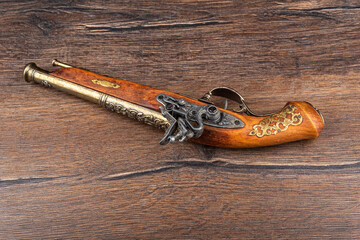 A replica of an old muzzle-loaded pistol on a wooden background.