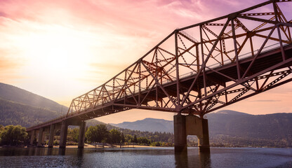 Big Orange Bridge over Kootenay River with Touristic Town in background. Sunrise Sky Art Render. Located in Nelson, British Columbia, Canada.