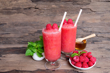 Raspberry banana smoothie red colorful fruit juice milkshake blend beverage healthy high protein the taste yummy In glass drink episode morning on a wooden background.