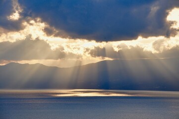Sun Rays pouring through the clouds into the sea. Crepuscular rays. Sun rays on golden hour to the sea. Colorful, partially cloudy orange sunset with sun rays piercing the clouds over Adriatic Sea