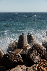 Strengthening the shore from erosion with concrete tetrapods. The seashore with concrete blocks. The element of water. Waves break on concrete.