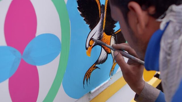 Artist painting eagle beak on truck side