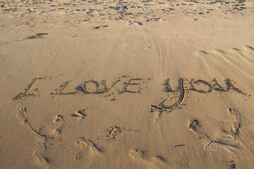 Words I Love You writing on the sand on beach against background. Love letters on the sand.
