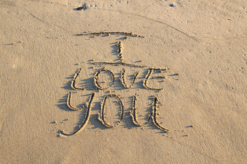 Words I Love You writing on the sand on beach against background. Love letters on the sand.