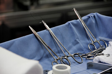 Close-up of scissors with thread and needle in an operating room.