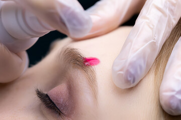 lamination of eyebrows for models, masters apply shampoo to the eyebrows to soften the hairs