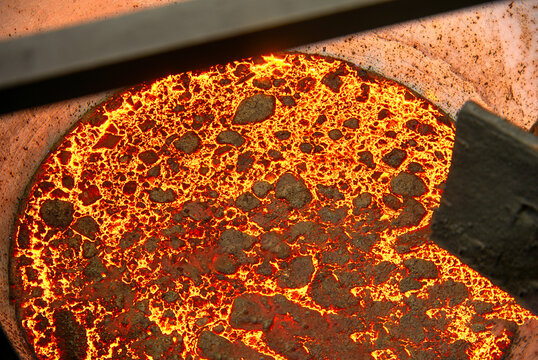 The surface of a hot liquid slag in a metallurgical ladle. Thick crust covered with trash net