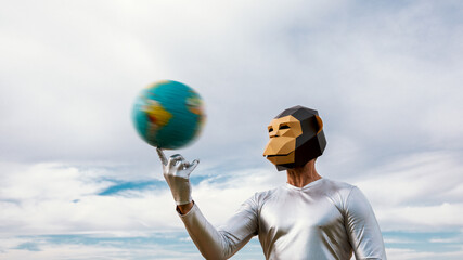 Person in geometric monkey mask spinning globe against sky