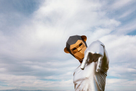 Person in geometric monkey mask gesticulating rock n roll against clouds