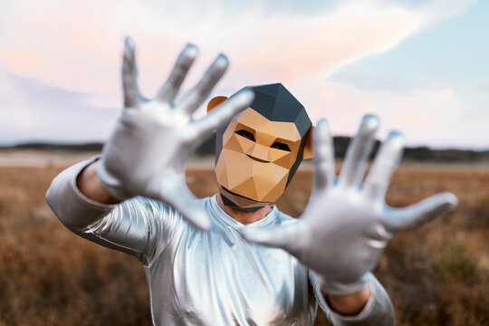 Person in monkey mask showing hands with bent thumbs