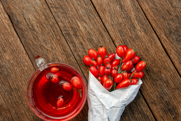 Dog rose, bunch branch Rosehips, types Rosa canina hips, essential oil and hot herbal tea cup