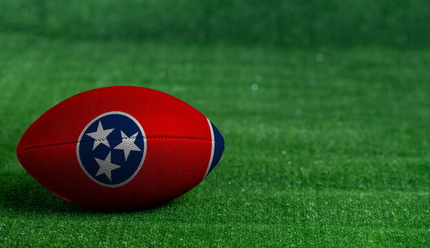 American football ball  with Tennessee flag on green grass background, close up