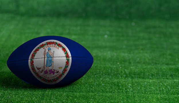 American football ball  with Virginia flag on green grass background, close up