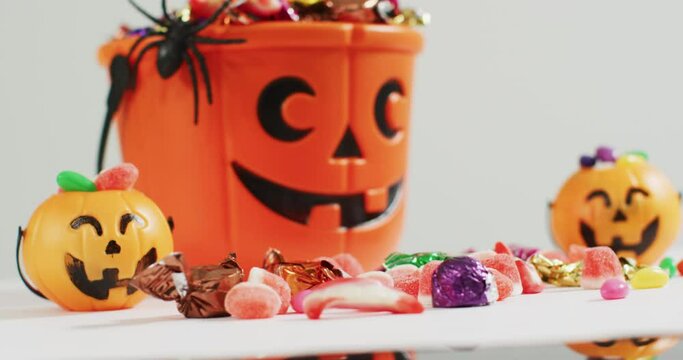 Scary halloween pumpkin printed bucket full of candies against grey background