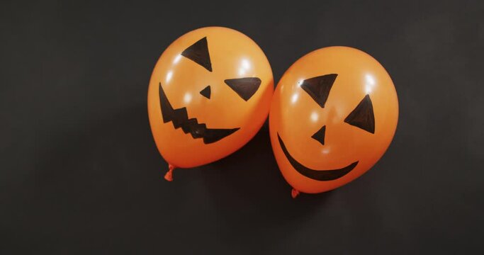 Two scary faces printed halloween balloons floating against grey background