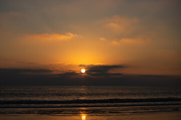 Calm sea with sunset sky and sun through the clouds over. Ocean and sky background, seascape.