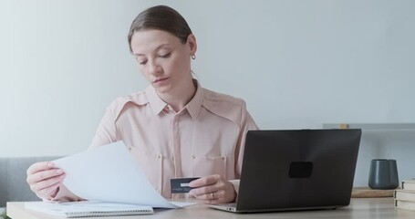 Focused young businesswoman holding financial document with trading statistics and investments profit results. Paying bills and domestic payments via electronic bank. Analyzing sales trading report - Powered by Adobe