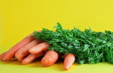Bunch of carrots on yellow background with copy space.