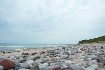 Fototapeta na wymiar Beautiful baltic beach shoreside landscape view with rocks cloudy overcast weather.