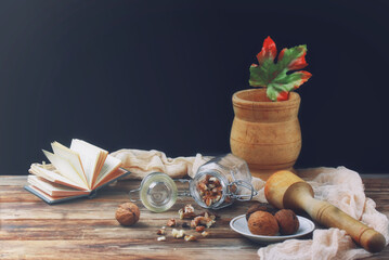 walnuts in glass jar on wooden table, mortar with pestle