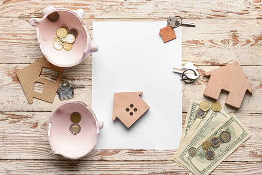 Blank paper, piggy bank with money and key from house on wooden background