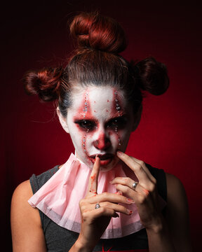 retrato mujer joven pennywise it mirando al frente sobre fondo rojo.  shh terror halloween makeup